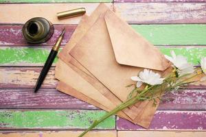 pila de sobre, flor y pluma estilográfica en la mesa foto