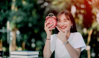 red alarm clock time management concept Female hands adjust or change the time on the clock to work. photo