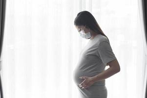 mujer embarazada joven con una máscara protectora y esperando un concepto de bebé, salud y maternidad foto