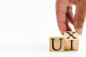 A wooden cube on a white table with text UI, UX. Concept of development and design and development, user interface, user experience, software, app. Copy space on left for a design, White background. photo