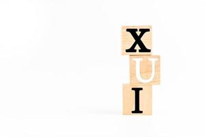 The Wooden cube on a white table with text UX, UI. Concept of development and design and development, user interface, user experience, software, app. Copy space on left for design, White background. photo