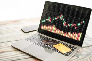 The graph displayed on a laptop screen and a credit card placed on the keyboard. Concept for trading stocks using credit cards and, online, rate, business, finance, selective focus, white background photo