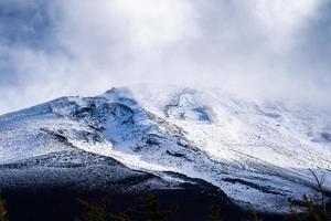 cierra la cima de la montaña fuji con cubierta de nieve y viento en la cima con podría en japón. foto