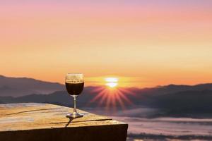 Red wine glass with the sunrise overlooking the mountains in northern of Thailand. photo