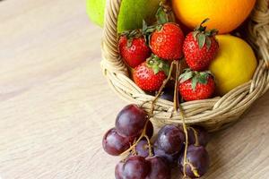 Assorted fresh fruits in basket on wooden table photo