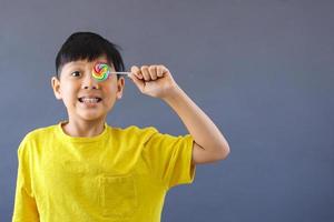 niño asiático feliz sosteniendo piruleta foto