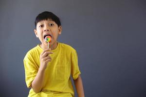 chico asiático lamiendo un caramelo de piruleta foto