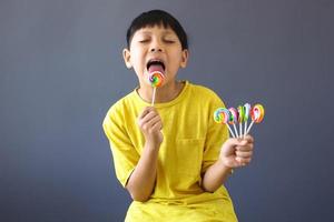 chico asiático lamiendo un caramelo de piruleta foto