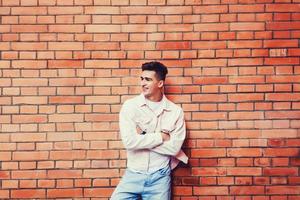 man posing against brick wall photo