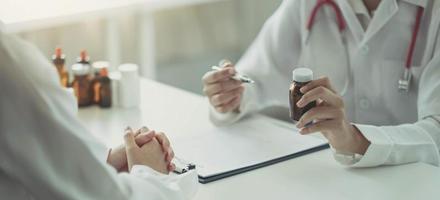 hombre y mujer confiados sosteniendo un frasco de pastillas mientras hablan con el paciente y revisan la medicina en la oficina.
