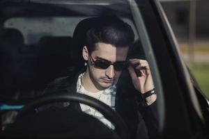 hombre con anteojos está sentado en un auto foto