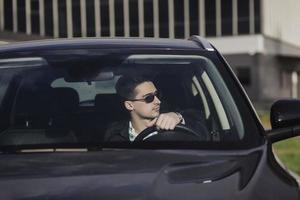 chico con gafas conduciendo su coche foto