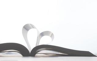 Soft light on surface of book pages in heart shape on white background photo