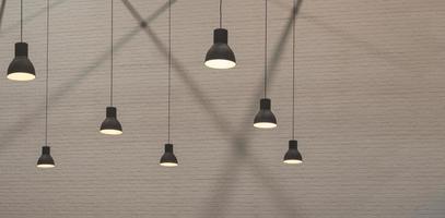 Group of vintage hanging lamps with light and shadow on surface of brick wall background in monochrome style photo