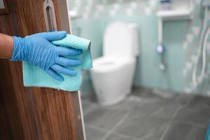 limpiar la manija del inodoro de la puerta en el inodoro con alcohol y un paño suave en la oficina y el hogar para proteger el coronavirus covid 19