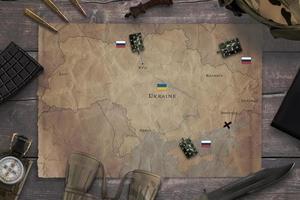 Map of the Russian invasion of Ukraine with military equipment on the table. Top view, flat lay concept composition photo