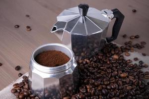 Disassembled geyser coffee maker on wooden surface. Coffee beans. photo