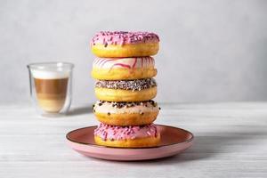 Glazed decorated donuts on plates and coffee latte or cappuccino photo
