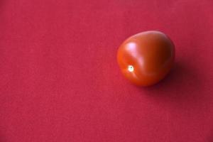 Juicy tomato on a red background photo