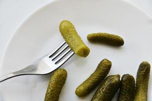 Green pickles on a white plate and a fork photo