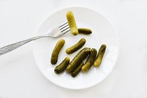 Green pickles on a white plate and a fork photo