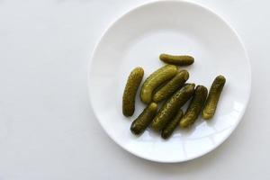 Green pickles on a white plate and a fork photo