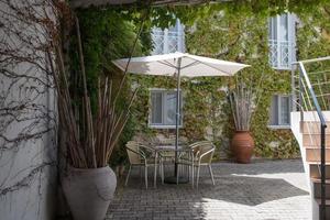 hermoso patio trasero con mesa, sillas y sombrilla. rincón verde con plantas trepadoras y macetas. Setúbal, Portugal