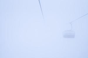 Ski lift disappearing into alps mountain through a dense fog photo