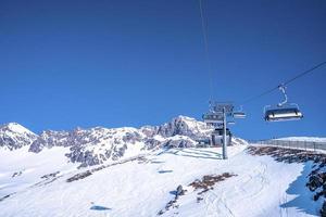 Ski lift on beautiful snowy mountain against blue sky photo