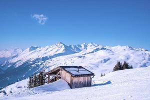 Small wooden house on snowy mountain against blue sky photo