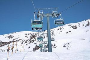 Chairlift on snowy landscape against clear sky on sunny day photo