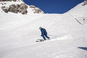Skier in sportswear having fun while skiing on snowy mountain photo