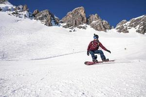Young snowboarder sliding down snowy slope on mountain at winter resort photo