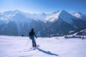 Male skier skiing on snowy landscape against mountain range photo