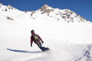 Rear view of skier in sportswear with backpack skiing on snowy mountain photo