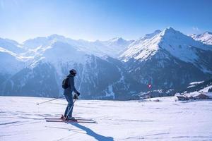Skier in sportswear skiing on slope against mountain range photo