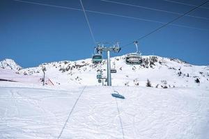 Ski lift on snow covered landscape against clear blue sky photo