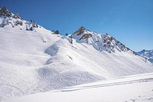 Ski tracks on snowy mountain range in alps photo