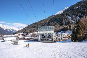 Skiers skiing towards station in alps during winter with dense forest photo