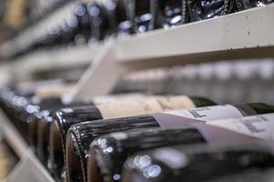 Variety of wine in glass bottles on racks in modern supermarket photo