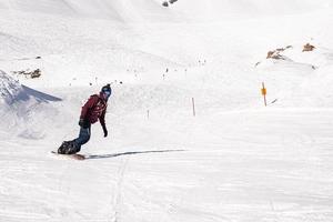 Young snowboarder sliding down snowy slope on mountain at winter resort photo