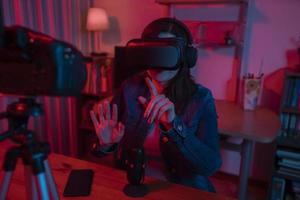 Beautiful Hispanic woman in front of a video camera recording a blog in her studio with red and blue lights inside her house photo