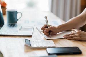 las mujeres de negocios escriben en el bloc de notas con bolígrafo para calcular los estados financieros dentro de la oficina. foto