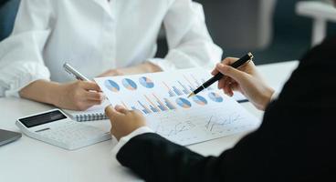 Business partnership coworkers using a report to analysis graph company financial budget report and cost work progress and planning for future in office room. photo