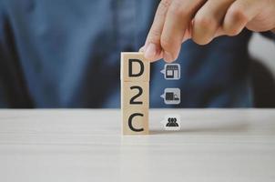 Hand put wooden cubes with Direct to Consumer D2C and icon on table and copy space.Business concepts. photo