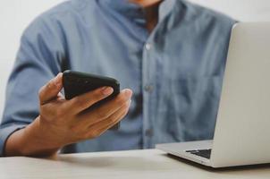 man using mobile smart phone and computer laptop searching internet, sending sms, using text messenger or online banking. photo