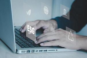 Escribiendo a mano en el símbolo del icono de la computadora portátil de esg en el concepto de pantalla virtual. esg medio ambiente gobierno social concepto de inversión que se centra en el medio ambiente, la sociedad y el buen gobierno. foto