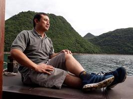 Handsome men sitting on the boat looking for a view is concept travel. Asia men traveling by boat looking around mountains over the beautiful lake. photo