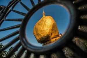 The golden rock pagoda or Kyaikhtiyo pagoda an iconic popular place in Mon state in Myanmar. View look through the fence. photo