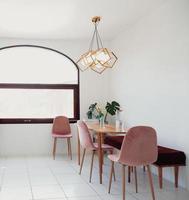 diseño de interiores de comedor de moda moderna en estilo minimalista con mesa de diseño, sillas, lámpara colgante de oro, pinturas abstractas y accesorios elegantes. foto